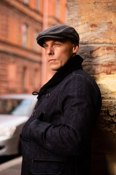 A man in a coat and cap walks around the city. stock photo
