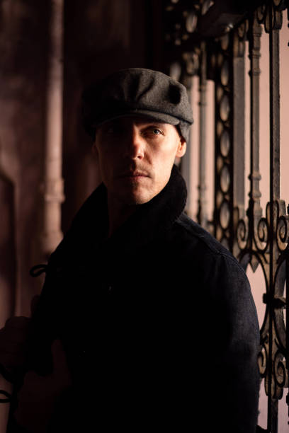 istock A man in a coat and cap walks around the city. 1354886490
