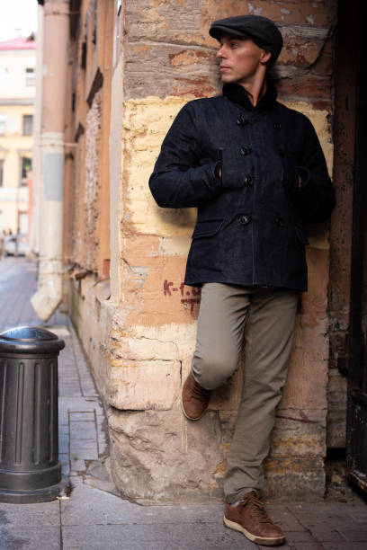 istock A man in a coat and cap walks around the city. 1354886658