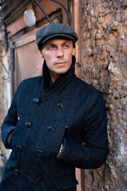 istock A man in a coat and cap walks around the city. 1354886705