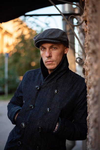 istock A man in a coat and cap walks around the city. 1354886753