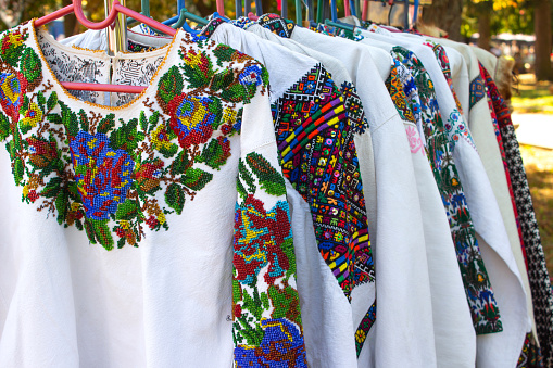 Close up view of vintage ukrainian clothes, vyshyvanka - traditional embroidered shirts on flea market or national festival and fair. Vintage goods on flea market, ukrainian culture in diaspora concept