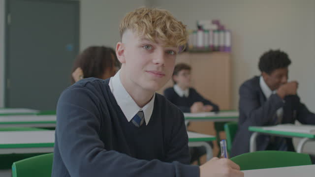 Candid close-up of teenage schoolboy working in classroom
