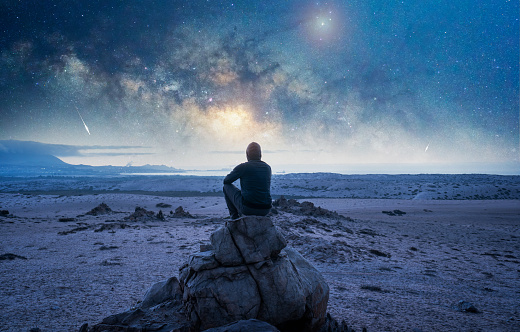 Man gazing into Milky way galaxy at night with unique rock formations in foreground. Shot in Australia.