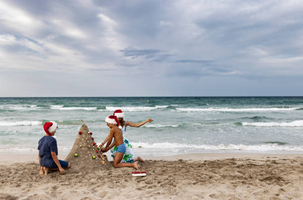 istock Kids decorating sand Christmas tree on summer Christmas 1354889955