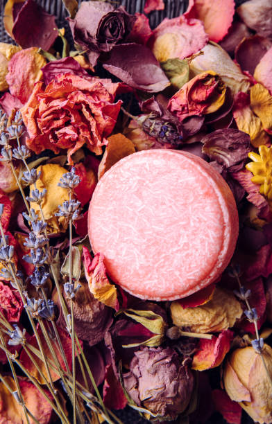 istock Pink color solid shampoo, conditioner bar on various dried flower petals, rose, lavender. Romantic vintage beauty set indoors. 1354890436