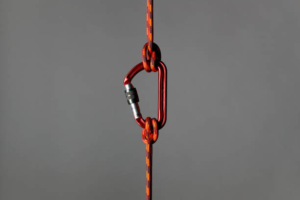 Safety concept Climbing rope with carabiner as safety concept against a grey background. carabiner stock pictures, royalty-free photos & images