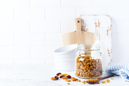 Oat granola with nuts and dried fruits to prepare a healthy breakfast on a bright kitchen table. Scandinavian white style. Selective focus
