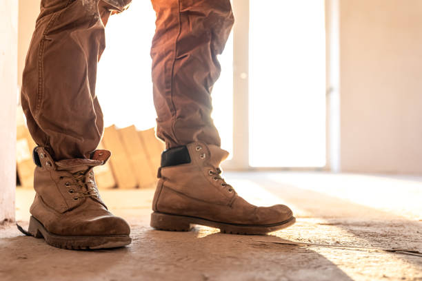istock Close-up of work shoes of a builder at a construction site, copy space. 1354891439