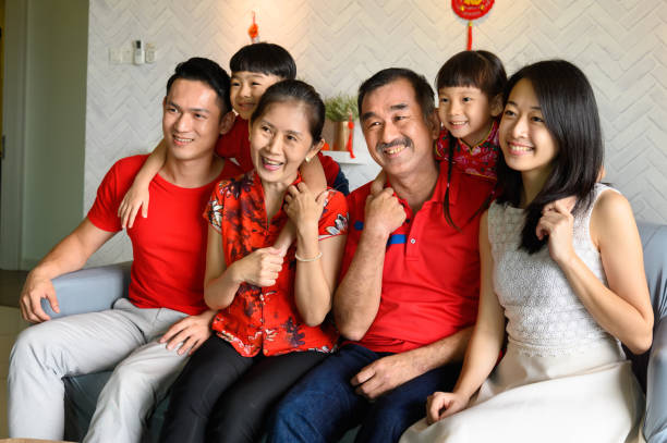 tre generazioni famiglia cinese asiatica che celebra il capodanno cinese - cheongsam chinese culture indoors looking at camera foto e immagini stock