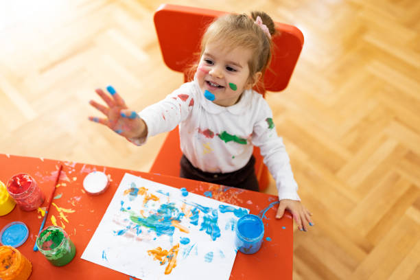 the little girl enjoys painting, she is all dirty but happy - one baby girl only fotos imagens e fotografias de stock