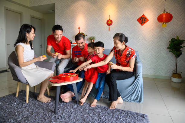 tre generazioni famiglia cinese asiatica che festeggia il capodanno cinese insieme a casa - cheongsam chinese culture indoors looking at camera foto e immagini stock