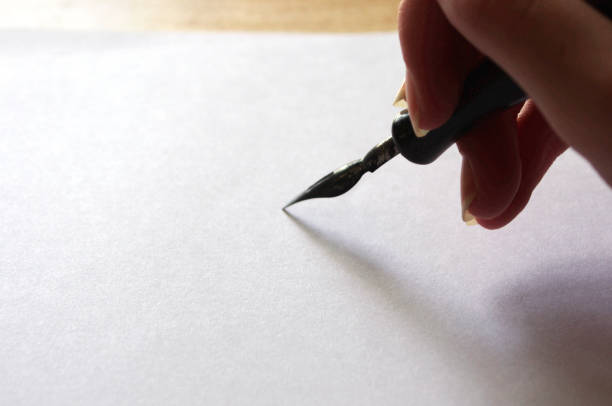 Calligraphy pen on blank colored paper with ink spots. Place for text. Top view.