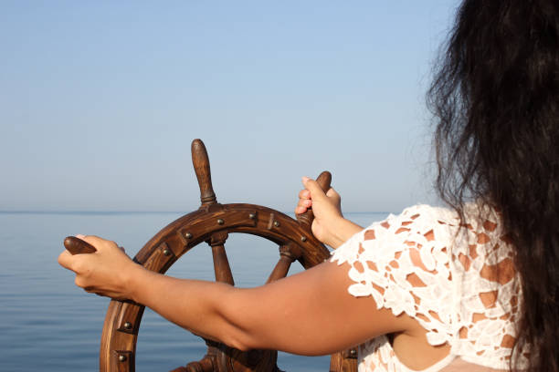 la ragazza controlla lo yacht, le mani sul volante, volantino su priorità bassa del cielo - helm rudder sailboat isolated foto e immagini stock