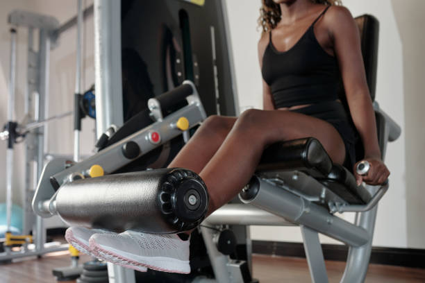 Woman Exercising on Leg Extension Machine Cropped image of fit young woman doing exercise on leg extension machine exercise machine stock pictures, royalty-free photos & images