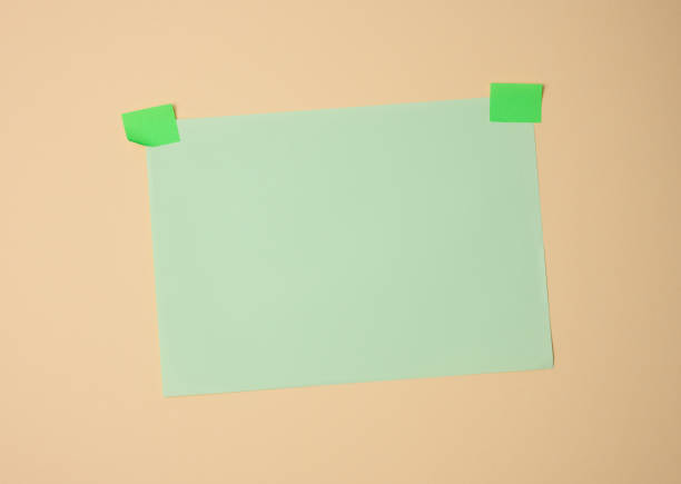 istock rectangular blank green sheet of paper glued with green sticky paper on light brown background 1354897200