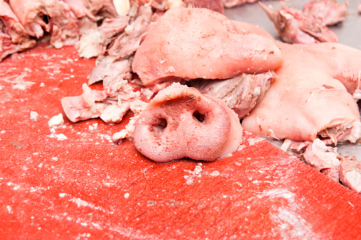 Cut pork snouts and ears in a butcher's shop. These head pork parts are ground and processed into sausage.