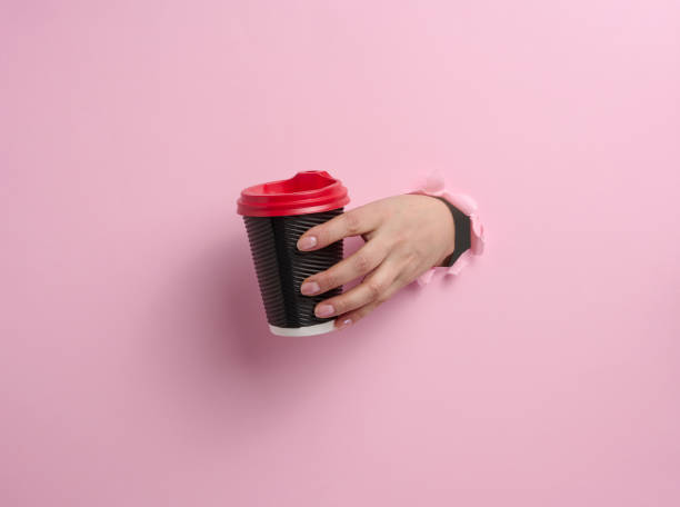 istock hand holds paper cardboard brown cup for coffee, pink background 1354897354