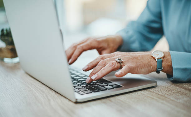 shot of an unrecognisable businesswoman using a laptop in a modern office - one old woman only imagens e fotografias de stock