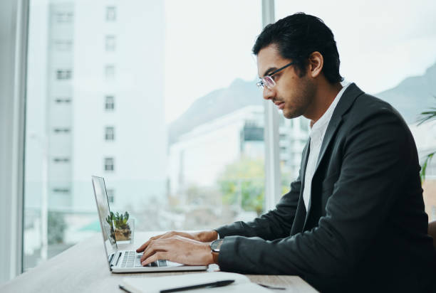 istock Shot of a young businessman using a laptop in a modern office 1354898571