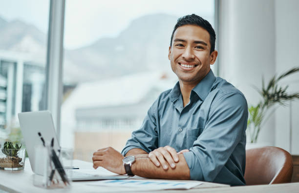 shot of a young businessman using a laptop in a modern office - mannen stockfoto's en -beelden