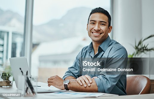 istock Shot of a young businessman using a laptop in a modern office 1354898581