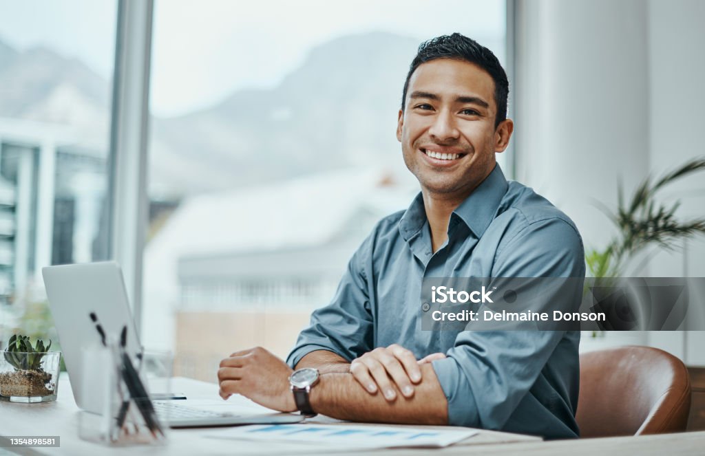 Shot of a young businessman using a laptop in a modern office A job well done is half the reward Businessman Stock Photo