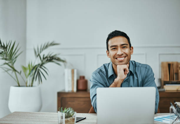 istock Shot of a young businessman using a laptop in a modern office 1354898587