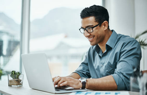 istock Shot of a young businessman using a laptop in a modern office 1354898596