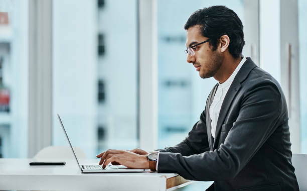 istock Shot of a young businessman using a laptop in a modern office 1354898606