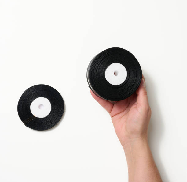 istock female hand holding rolled up black silk ribbon on white background 1354899170