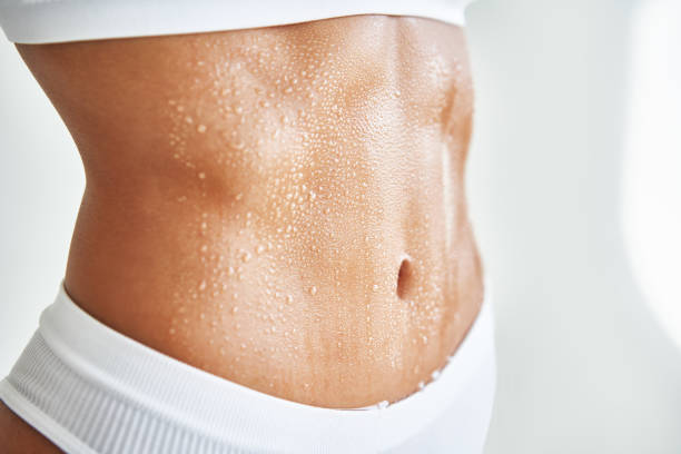 Close up belly of a beautiful sporty girl in drop of sweat or water on skin stock photo
