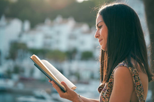 istock young woman reading a book at sunset on her terrace 1354900210