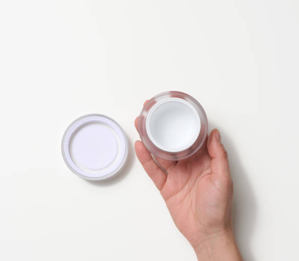 istock female hand holding  empty white plastic jar. Packaging for cream, gel, serum 1354901332