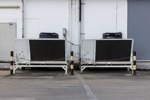 istock Air conditioner compressor installed in old building. Cooling towers in data center building. Industrial cooling towers or air cooled water chillers with piping system 1354901903