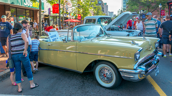 Moncton, New Brunswick, Canada - July 10, 2015  :  a small group of people stand near and look at the 1957 Chevrolet Bel Air convertible parked in downtown Moncton during 2015 Atlantic Nationals, Moncton, New Brunswick, Canada.