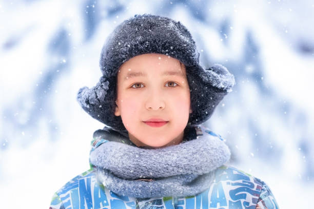 istock Boy's portrait in snowy hat on winter forest background 1354902363