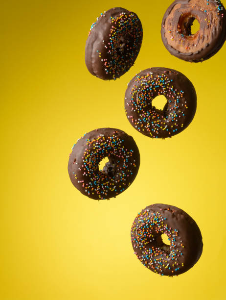 istock chocolate round donuts with multicolored sugar sprinkles levitate on a yellow background 1354903787