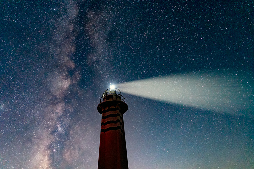 Lighthouse Under the Milky Way near a small town