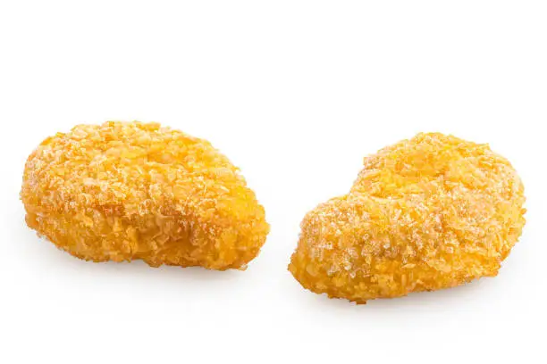 Two frozen gluten free cornflake crumb chicken nuggets isolated on white.