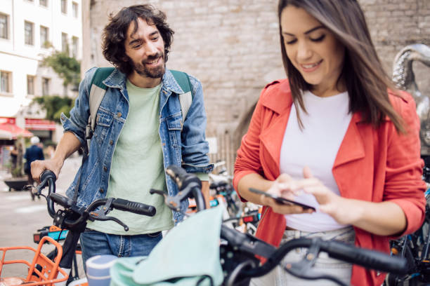 Young couple on a journey using a mobile app for renting E-bikes Young couple renting e-bikes to explore Barcelona. rent a bike stock pictures, royalty-free photos & images