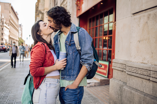 Portrait of a young couple in Barcelona kissing and enjoying their journey.