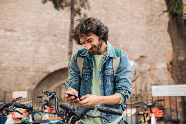 Young man on vacation renting an E-bike Young tourist renting an e-bike to explore Barcelona. rent a bike stock pictures, royalty-free photos & images