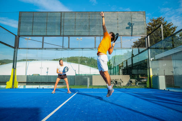 partido de pádel mixto en una pista de pádel de hierba azul - 
hermosa chica y hombre guapo jugando al pádel al aire libre - tennis in a row team ball fotografías e imágenes de stock