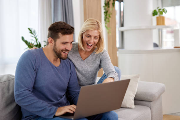 istock Young couple using a laptop while relaxing on the sofa at home 1354908006