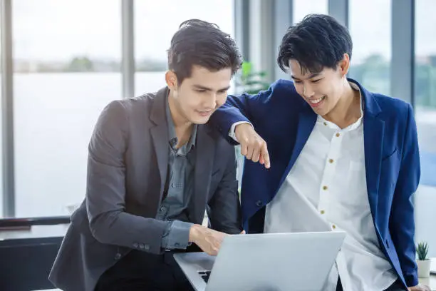 Happy Company Young Asian businessman and coaching personal secretary assistant tomboy lesbian and LGBT partners while working together with laptop computer and strategy in business in office