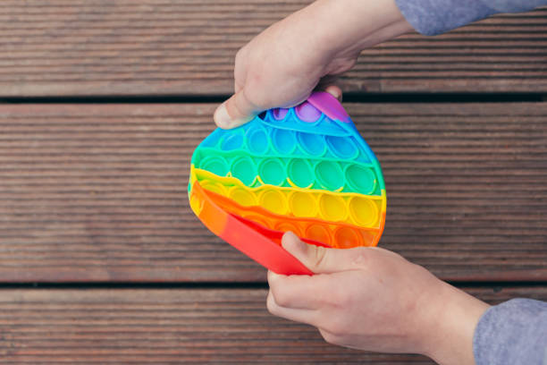 foto de cerca de niños jugando juego anti estrés pop it, burbujas de colores - board game spinner fotografías e imágenes de stock