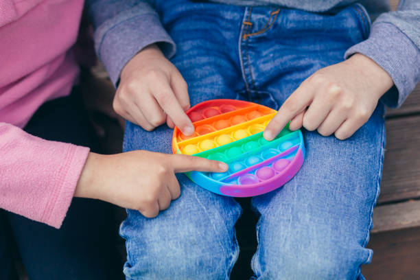 foto de cerca de niños jugando juego anti estrés pop it, burbujas de colores - board game spinner fotografías e imágenes de stock