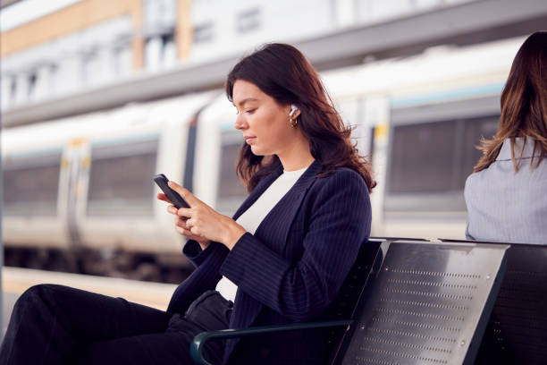 istock Two Businesswomen Commuting To Work Waiting For Train On Station Platform Looking At Mobile Phones 1354912728