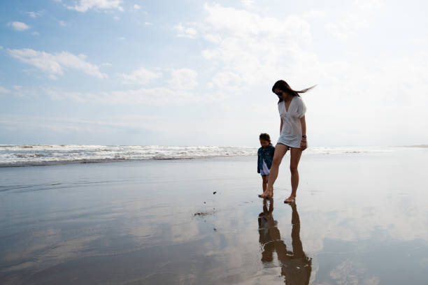 istock Mother and child walking on the beach 1354914287